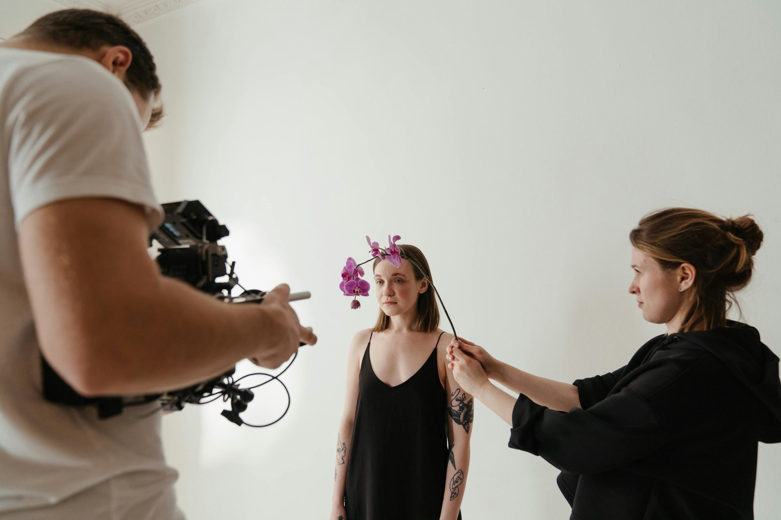 A photoshoot with a female model and orchid headpiece, captured in a studio setting.